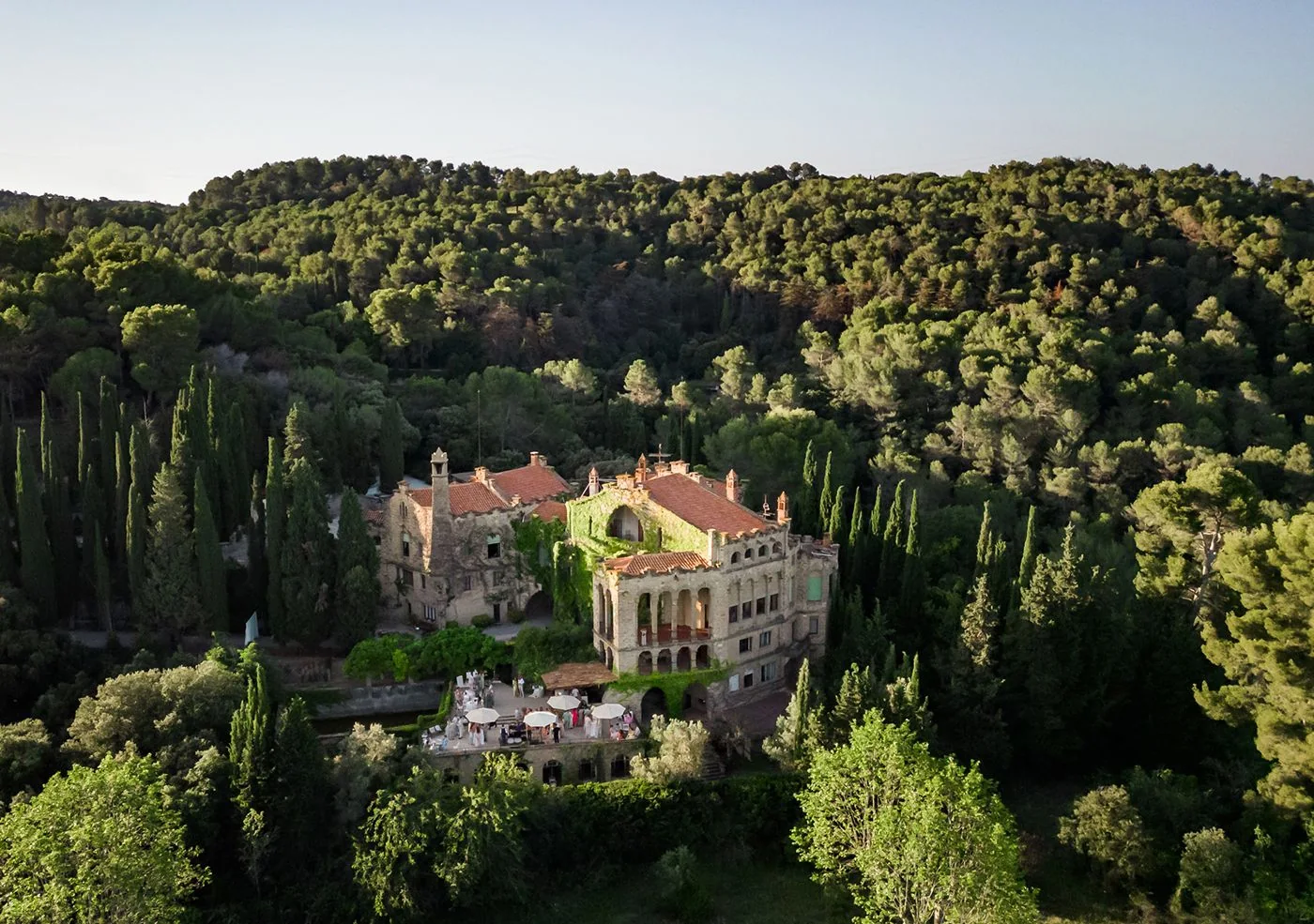 Aerial view of La Baronia, a stone manor set among the forested hills near Barcelona at golden hour